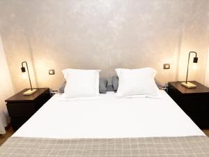 a bed with two nightstands and two white pillows at Elegante apartamento con piscina A un paso de Sevilla San Miguel in Camas +23 photos