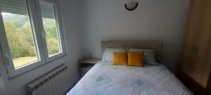 a bedroom with a bed with two pillows and a window at Rural Household Baltic in Mojkovac