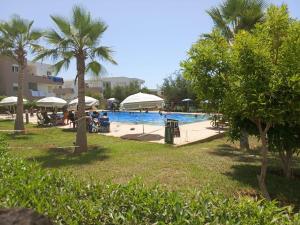 a pool at a resort with palm trees and people at Charming 2 bedrooms Appartment in Agadir nʼ Aït Sa