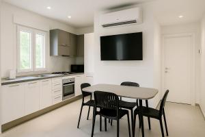 a kitchen with a table and chairs and a tv on the wall at Modern apartment with parking in Lignano Sabbiadoro