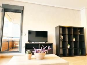 a living room with a television and a table at Elegante apartamento con piscina A un paso de Sevilla San Miguel in Camas