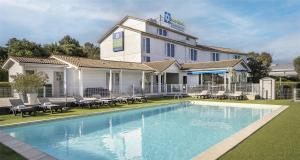 a hotel with a swimming pool in front of a building at Sure Hotel by Best Western Nimes Est in Nîmes