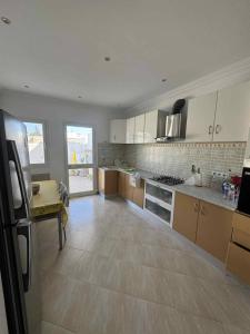 a large kitchen with white cabinets and a wooden floor at Maison cosy et moderne in Dar Tahar Zaouch