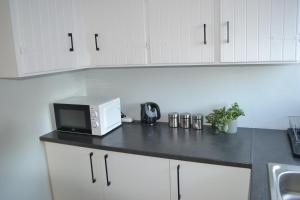a kitchen with white cabinets and a microwave on a counter at The Sparrow Room in East London