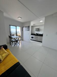 une grande chambre blanche avec une table et une cuisine dans l'établissement Apto Vista Mar | 200m Praia | 7 minutos do Parque, à Penha 32 autres photos
