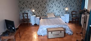 a bedroom with a bed and a tv and chairs at Les Figuiers Bleus in Cravencères