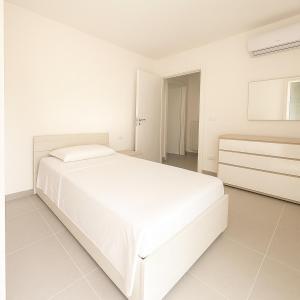 Dormitorio blanco con cama blanca y vestidor en Garden apartment with parking, en Lignano Sabbiadoro