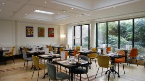 a dining room with tables and chairs and windows at Hôtel Pont Royal Paris in Paris