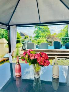 een vaas met bloemen op een glazen tafel met twee flessen bij KVS Concept Hébergement haut de gamme près du Circuit des 24 Heures du in Écommoy