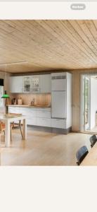 a kitchen with white cabinets and a table in a room at Bøtøstrand feriehus 90 in Marielyst +12 photos