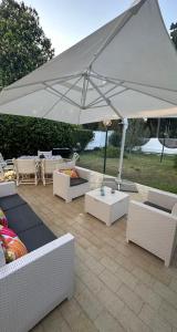 a white umbrella over a patio with couches and tables at Villetta Tina in Siponto