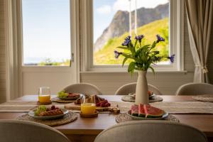 a table with food and a vase with flowers on it at Reinefjorden Family House in Reine