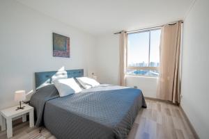 Una habitación blanca con una cama y una ventana en Loica Host - Smart, en Santiago