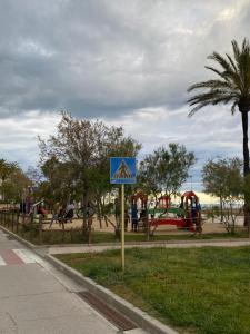 a blue sign in a park with a playground at Apat sombrero A Cunit Beach in Cunit
