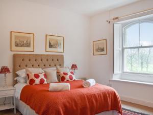 a bedroom with a bed with a orange blanket and a window at West Lodge in Barnard Castle