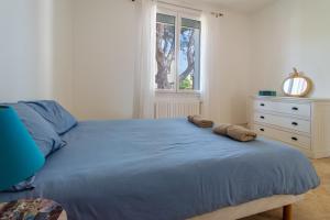 ein Schlafzimmer mit einem blauen Bett, einer Kommode und einem Fenster in der Unterkunft Somptueuse villa piscine terrain de pétanque à 10 min de Sète in Frontignan + 22 Fotos