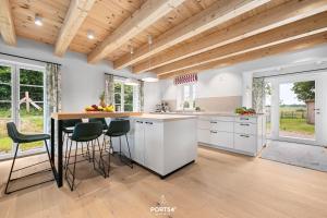 une cuisine avec des armoires blanches et un comptoir avec des tabourets dans l'établissement Ferienhaus ReetCottage 24 Dörphof, à Dörphof