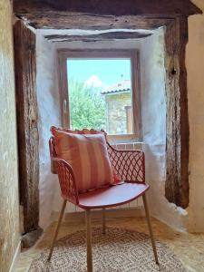 une chaise avec un oreiller assis devant une fenêtre dans l'établissement Chambre d'hôte, suite duplex 50 m2 en pleine nature sur les hauteurs de Brioude, à Champagnac-le-Vieux