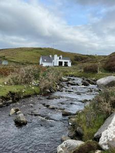 a house on a hill next to a river at Glenurla Valley Cottage in Ballycastle