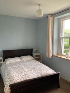 a bedroom with a bed and a window at Glenurla Valley Cottage in Ballycastle +25 photos