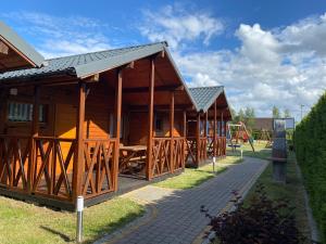 a row of wooden lodges with a playground at Plażowa Domki in Mielenko