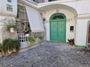 Corte San Giovanni - Alloggio per vacanza perfetta في فيتري: باب أخضر على مبنى أبيض به نباتات الفخار