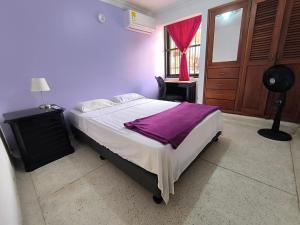 a bedroom with a bed with a purple blanket on it at CasaNegreteHostalBoutique in Cartagena de Indias