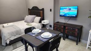 a bedroom with a bed and a table and a tv at GreenMarket Studio in Knysna