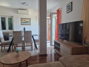 a living room with a television and a table with chairs at Apartment Brač in Sutivan