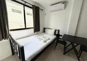 Cama pequeña en habitación con escritorio y ventana en Patong Canal Villa R208, en Patong Beach
