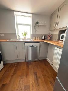 a kitchen with white cabinets and a wooden floor at Fresh comfy space, feel at home. in Gravesend +20 photos