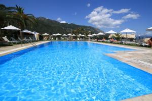 a large blue swimming pool with umbrellas at Hotel Yannis Corfu in Ipsos