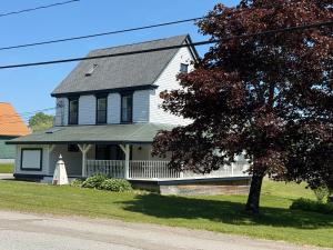 a white house with a black roof and a tree at Fundy Footprints in Saint Martins