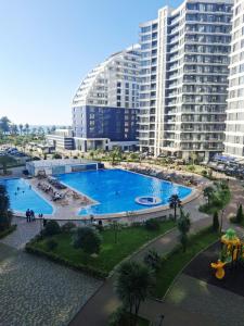 a large swimming pool in front of a large building at Bright Spacious Family Apartment in White Sails in Batumi