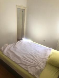 a bed with a white sheet on it in a room at Stan na dan in Kragujevac
