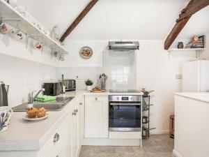 a kitchen with white cabinets and a sink at Hingham Mill Cottage in Wadebridge +16 photos