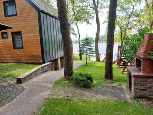 a house with trees and a sidewalk next to the water at Domek letniskowy "BRDA" - Ostoja Ślesin in Półwiosek Stary