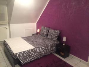 a bedroom with a bed with a purple wall at L'Eden Orly Aéroport in Thiais