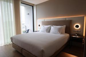 Un dormitorio con una gran cama blanca con una gran ventana. en Oporto Fly Hotel, en Maia