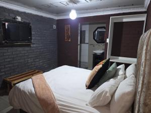 a bedroom with a bed with pillows and a tv at EzekMary Res in Polokwane