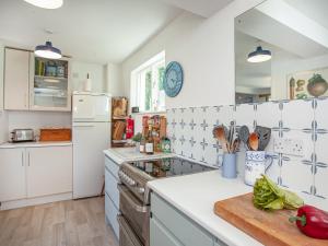 eine Küche mit weißen Schränken und einem Herd mit Backofen in der Unterkunft The Cottage in Salcombe