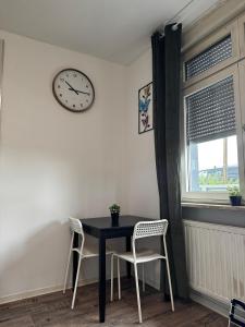 a dining room table with two chairs and a clock at Deluxe Apartements Bobenheim Roxheim in Bobenheim-Roxheim +3 photos