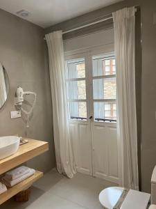 ein Bad mit einem Waschbecken und eine Tür mit einem Fenster in der Unterkunft Cantábrico Fonsagrada in A Fonsagrada