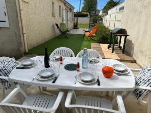 a white table with plates and glasses on a patio at La Jalé in Saint-Georges-dʼOléron