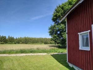 a red building with a window next to a field at Agroturystyka Kozianka in Iława