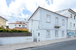 una casa bianca sul lato di una strada di Cozy Beach Apartment a Estoril