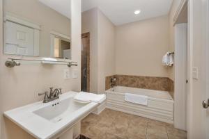 a white bathroom with a sink and a tub at Sea Gate #205 in Demere Park +27 photos