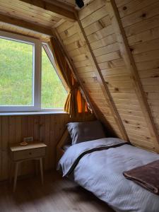 a bed in a wooden room with a window at Evergreen Tiny Homes in Peje