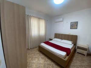 Schlafzimmer mit einem Bett mit weißen Wänden und einem Fenster in der Unterkunft Hajdini Apartament & Studios in Sarandë