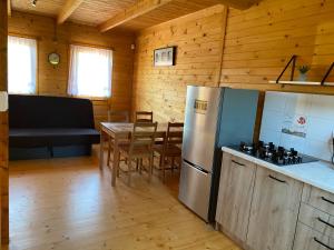 a kitchen and dining room with a refrigerator and a table at Plażowa Domki in Mielenko